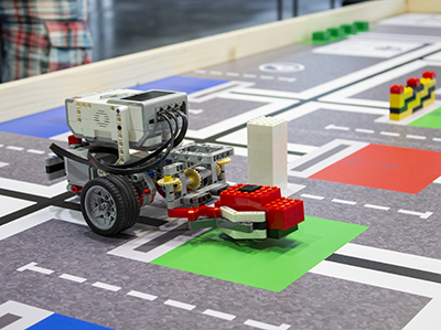Roboter hebt ein Lego-Objekt auf WRO-Wettbewerbsarena hoch
